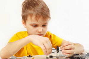 Little serious engineer plays with mechanical constructor at table